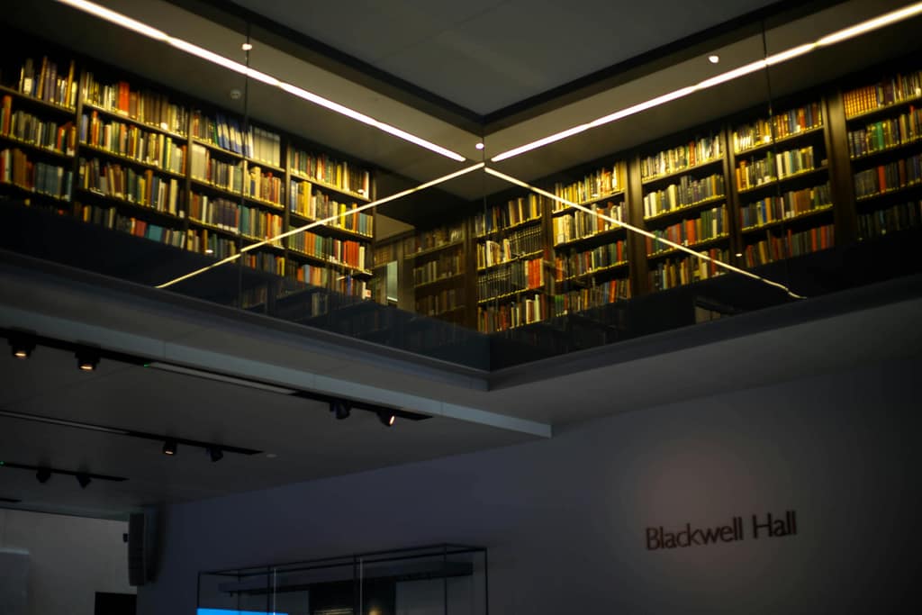Interior view of a modern library featuring bookshelves and glass reflections.