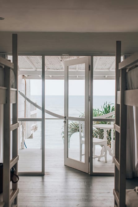 pexels-photo-6774009-6774009 Modern beachside room with open doors leading to a serene ocean view.